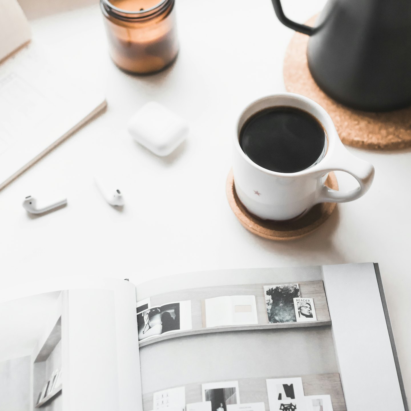 Escritorio minimalista con café, auriculares y una vela.